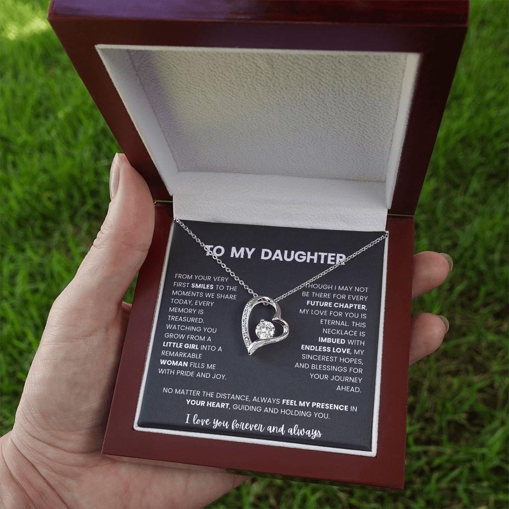 Necklace with heart design in a luxury jewelry box held by a hand against a grassy background