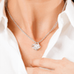 “Mom Love Knot Necklace from Son with cubic zirconia pendant on silver chain, worn by woman in white blouse – elegant jewelry gift for mothers”