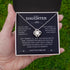 Necklace in a box with a message for a daughter, held by a hand against a grass background.